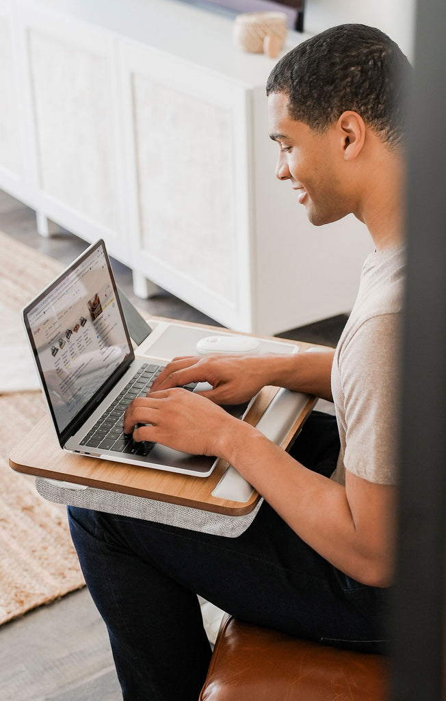 Man using a laptop on a premium lap desk in a modern living room.