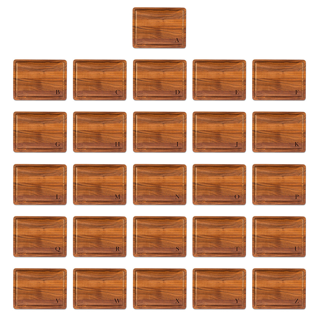 Set of 26 walnut cutting board letter engravings in the bottom right corner using baskerville font, from A to z on a white background
